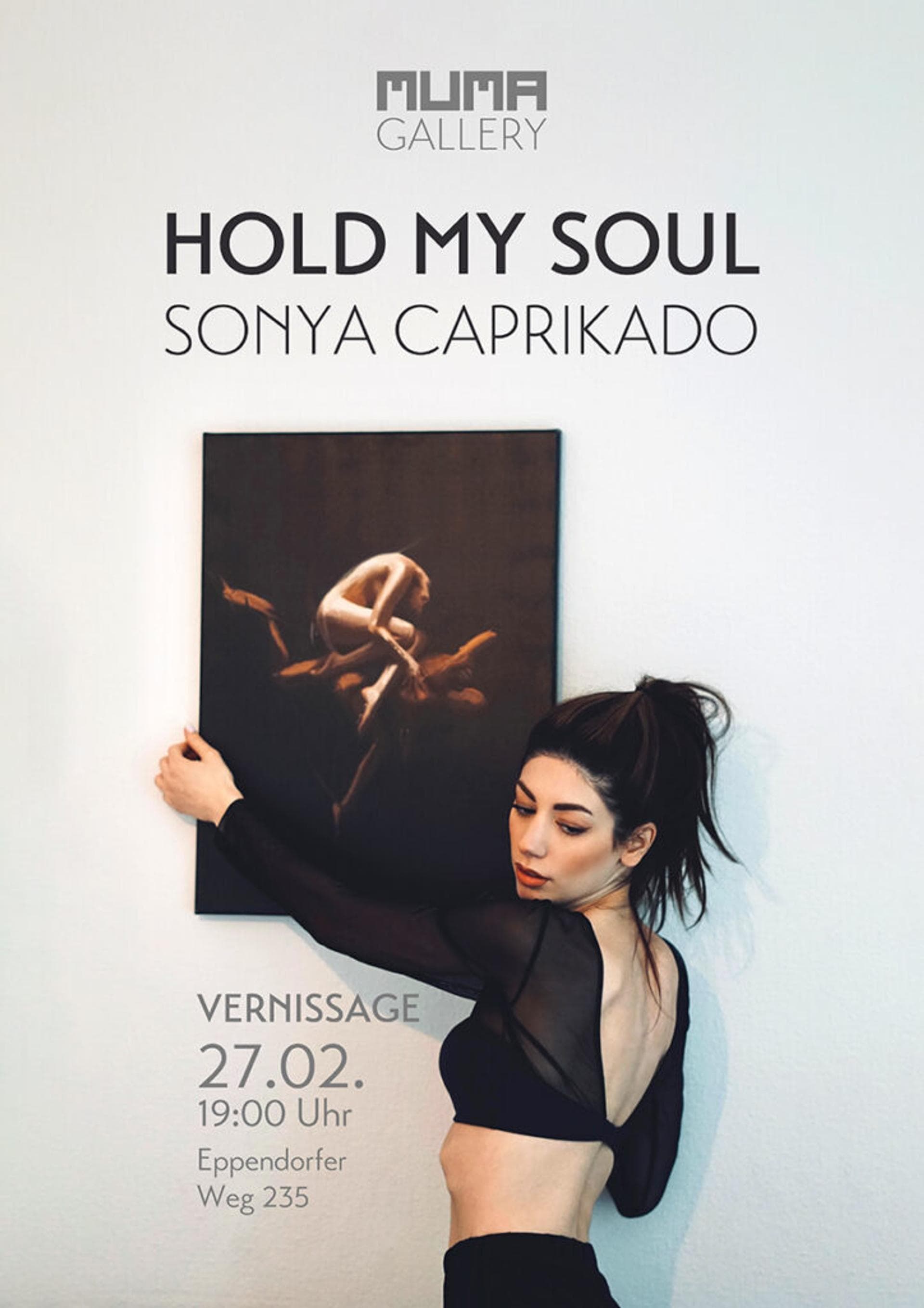 Sonya Caprikado holding one of her images against a white wall